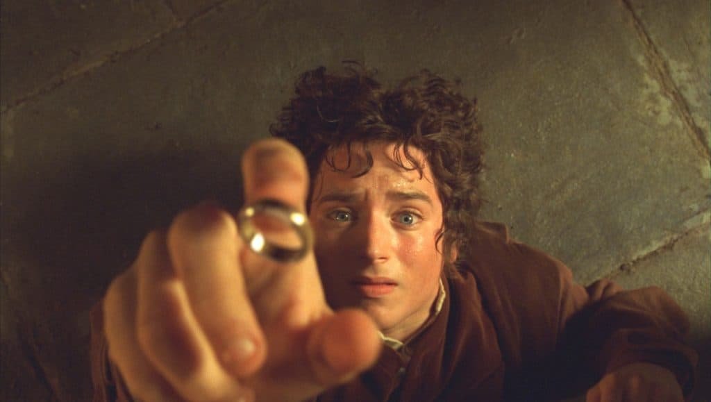 Image shows a close-up of the character Frodo taking a ring in the movie The Lord of the Rings