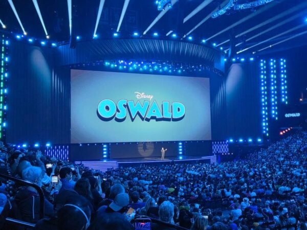 A man stands on stage in front of a screen with the words 